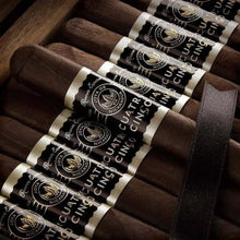 Load image into Gallery viewer, Full-flavored Joya de Nicaragua Cuatro Cinco Petite Corona cigar with a dark wrapper and detailed band, displayed on a wooden surface.